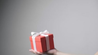 Childs 'ın eli kurdeleli kırmızı hediyeyi tutuyor. Noel, yeni yıl, doğum günü sürprizi