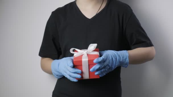 Kleine meisjes handen in blauw beschermende handschoenen geven geschenk doos met wit lint — Stockvideo