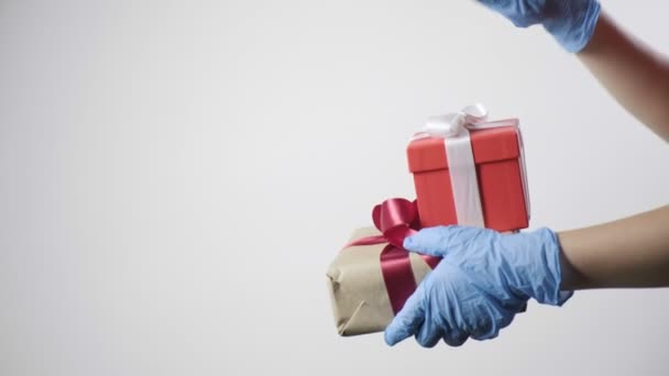 Ręce w niebieskich rękawiczkach ochronnych dają pudełka z wstążkami. COVID-19 Boże Narodzenie — Wideo stockowe