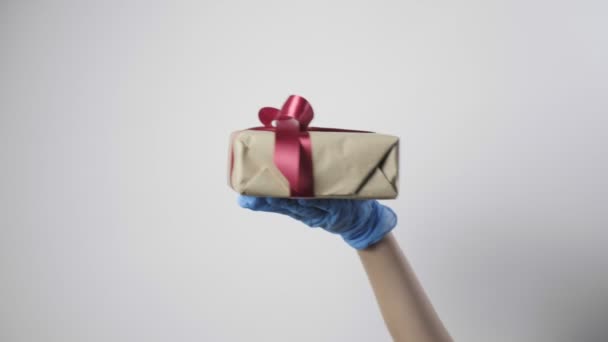 戴蓝色防护手套的人的手带礼品盒 Covid 19新年 圣诞节 情人节惊喜 检疫安全 新常态 孩子的背景是白的 — 图库视频影像