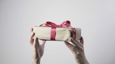 Erkeklerin elleri kırmızı kurdeleli hediyeyi tutuyor. Noel, yeni yıl, doğum günü sürprizi