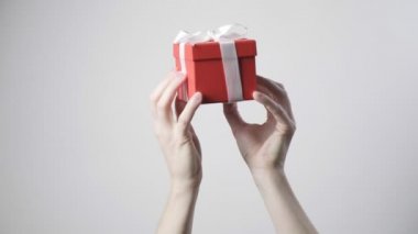 Erkeklerin elleri kırmızı kurdeleli hediyeyi tutuyor. Noel, yeni yıl, doğum günü sürprizi