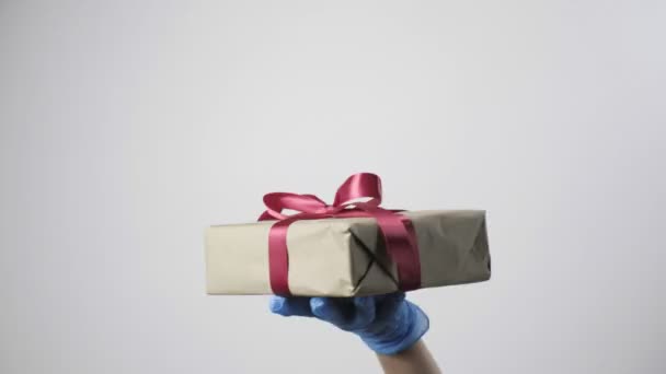 파란 장갑을 손에 들고 리본이 달린 선물 상자를 줍니다. 코비 디 19 세 크리스마스 — 비디오