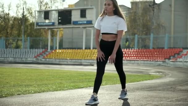 Smal asiatisk kvinna i aktiva kläder sträcker kroppen utomhus innan löpning på stadion — Stockvideo