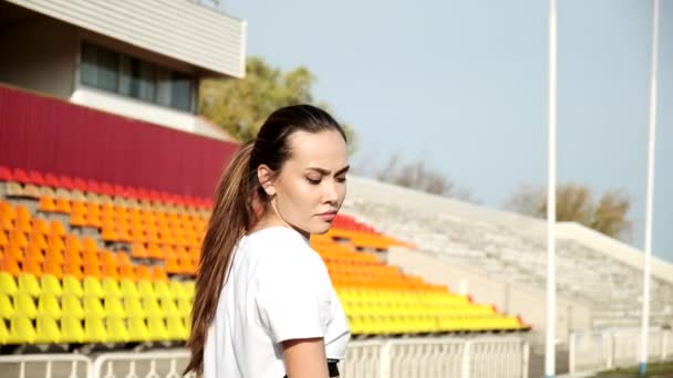 Jovem asiático feminino vira cabeça sobre ombro no fundo de assentos no estádio — Vídeo de Stock