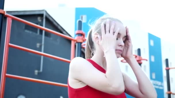 Portrait of young fit blond busty girl with ponytail in red top at sports ground — Stock Video
