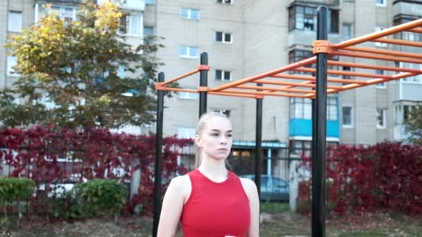 Portrait of young fit blond busty woman with ponytail standing at sports ground — Stock Footage Portrait of young fit blond busty woman with ponytail standing at sports ground Video Clip