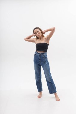 Siyah bluzlu, uzun saçlı, beyaz kot pantolonlu çekici Asyalı kadın.