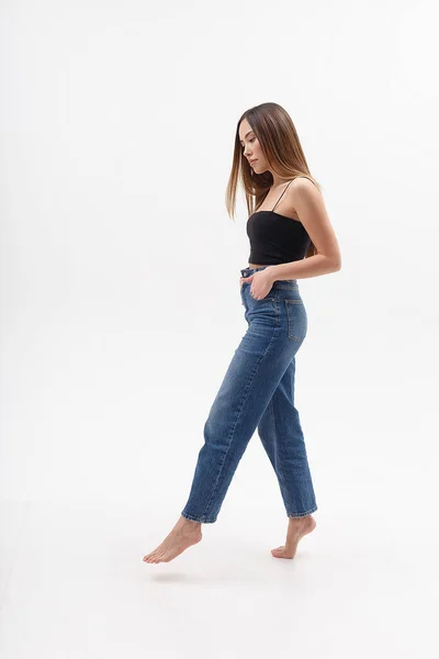 Ung attraktiv asiatisk kvinna med långt hår i svart topp, blå jeans på vit — Stockfoto