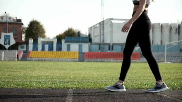 陸上競技場のランニングコースを歩いている若い女性の足です。スポーツ — ストック動画