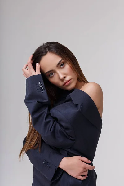 Ung attraktiv asiatisk kvinna i blå kostym isolerad på grå studio bakgrund — Stockfoto