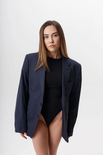 Jovem atraente asiático mulher no preto bodysuit e azul terno isolado no branco — Fotografia de Stock