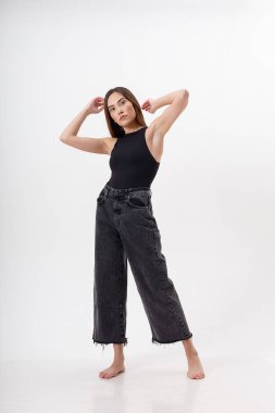 Beyaz arka planda siyah elbiseli, uzun saçlı, genç, çekici Asyalı kadın.