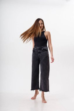 Beyaz arka planda siyah elbiseli, uzun saçlı, genç, çekici Asyalı kadın.