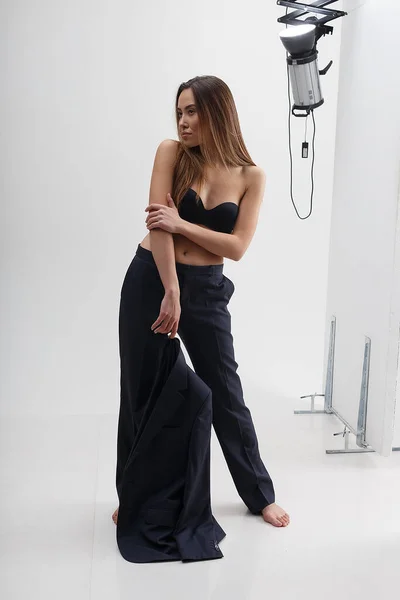 Young asian woman with long hair in bra and suit in front of studio equipment — Stock Photo, Image