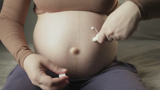 Donna incinta che disegna il simbolo del cuore con la crema bianca sulla pancia — Video Stock