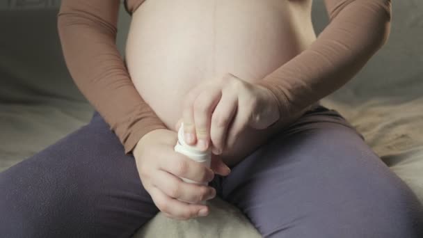 Pregnant woman sitting on couch, opening bottle of pills, showing medicine — Stock videók