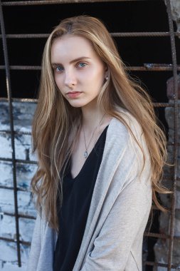 young natural pretty lady with blue eyes posing in front of metal grid fence