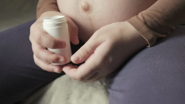 Pregnant woman with big belly sitting on couch, showing bunch of pills in palm — Stock videók