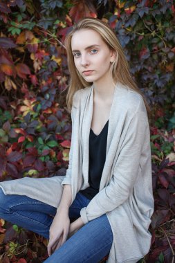 natural caucasian pretty lady with blue eyes posing in front of bush foliage