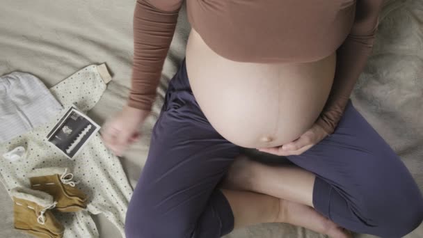 Верхня голка очікуваної вагітної жінки з великим животом, дивлячись на ультразвукове сканування — стокове відео