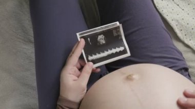 Koca göbekli hamile bir kadının evde ultrason taramasına bakmasını bekliyorum.
