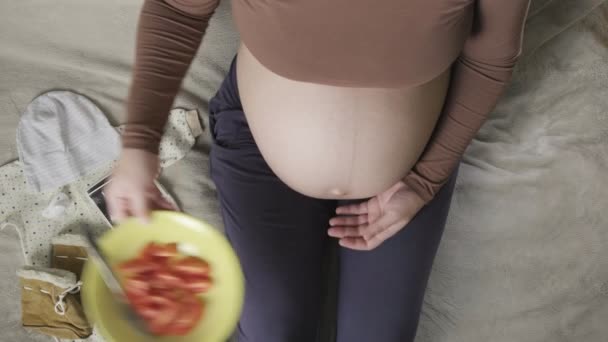 Top vew of expecting pregnant woman with large belly eating tomatoes at home — Stock Video