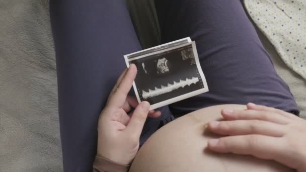 Terhes nő nagy hasa nézi ultrahang vizsgálat otthon — Stock videók