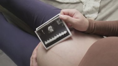 Koca göbekli hamile bir kadının evde ultrason taramasına bakmasını bekliyorum.