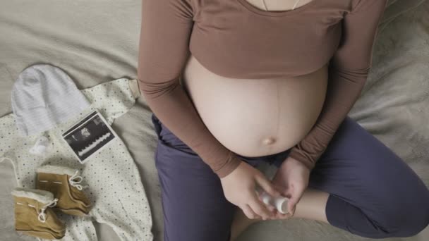 Terhes nő nagy hasa ül a kanapén otthon, gyógyszert szed — Stock videók