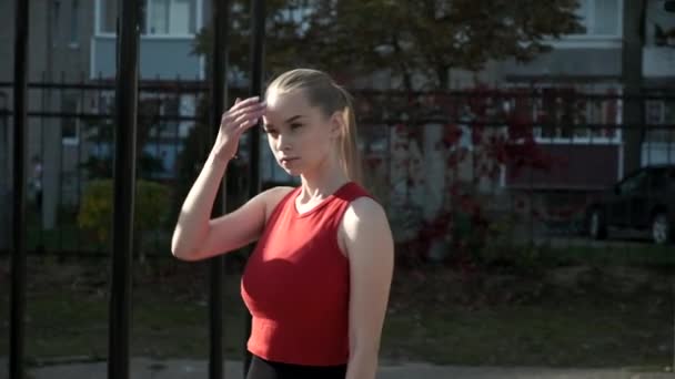 Mladá fit busty žena s culíkem stojí na sportovním hřišti, škrábance na čele — Stock video