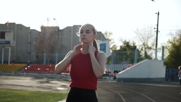 Sottile giovane atleta con coda di cavallo in abbigliamento sportivo che cammina su pista da corsa — Video Stock