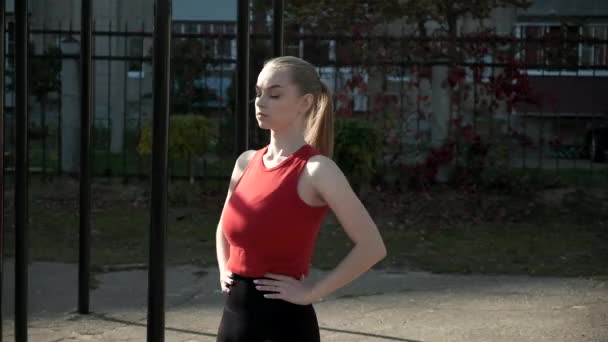 Portrét mladé fit blond busty žena s culíkem stojící na sportovním hřišti — Stock video