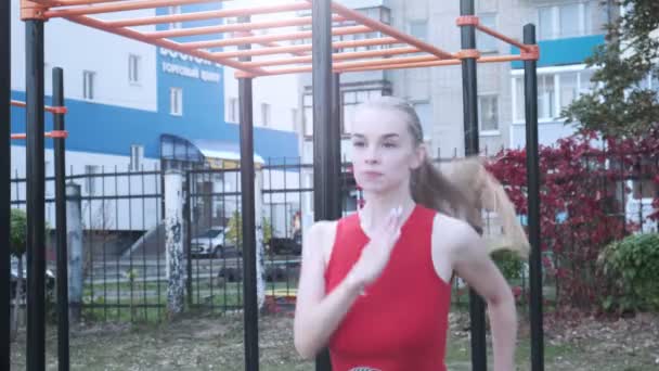 붉은 운동복을 입고 달리고, 단거리 달리 기를 하고 있는 코카서스의 아름다운 여성 — 비디오