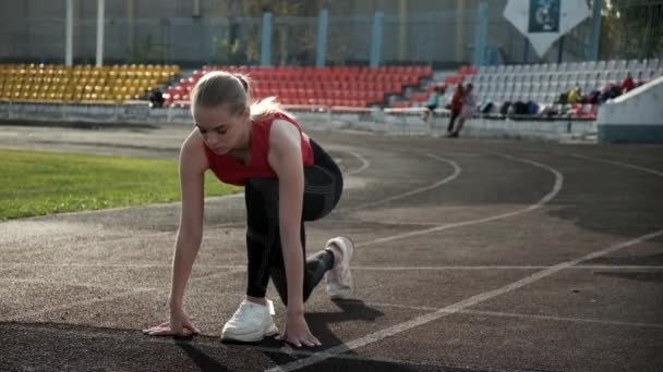 Тонка фітнес бігунка в спортивному одязі стоїть на стартовій позиції на трасі — стокове відео