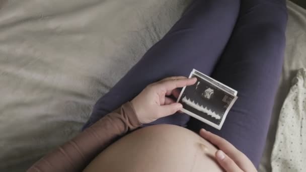 Attesa donna incinta con grande pancia guardando ecografia a casa — Video Stock