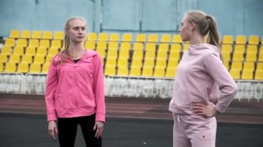 Spor kıyafetlerinde gülümseyen ve stadyumda konuşan tek yumurta ikizleri.