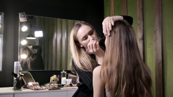 迷人的高加索化妆师在美容院为年轻女性化妆 — 图库视频影像