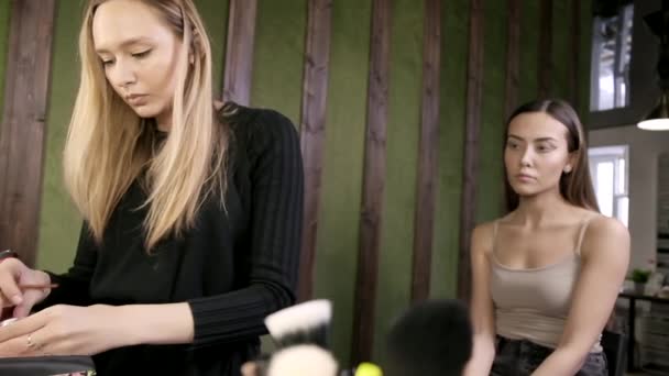 Attrayant caucasien maquilleur faire maquillage pour asiatique femelle dans salon de beauté — Video