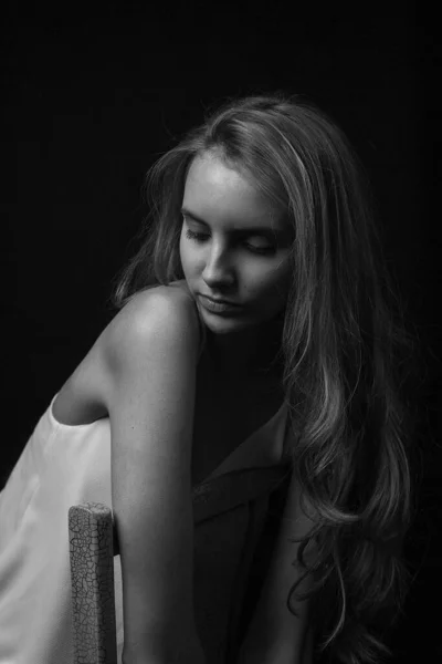 Joven bonita mujer con el pelo largo en camisa sentado en silla sobre fondo negro —  Fotos de Stock