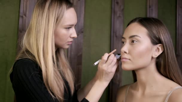 Maquillaje artista haciendo maquillaje para asiático mujer con ojo lápiz en salón de belleza — Vídeos de Stock