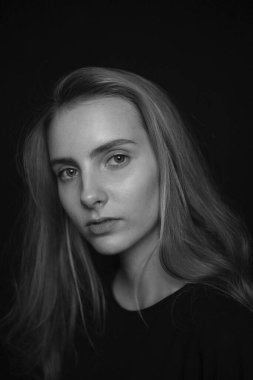 Uzun saçlı, siyah pozlar veren hoş, genç bir kadın.