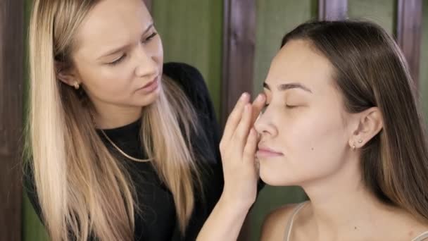 Визажистская работа, нанесение увлажняющего крема на лицо клиента - азиатская женщина — стоковое видео