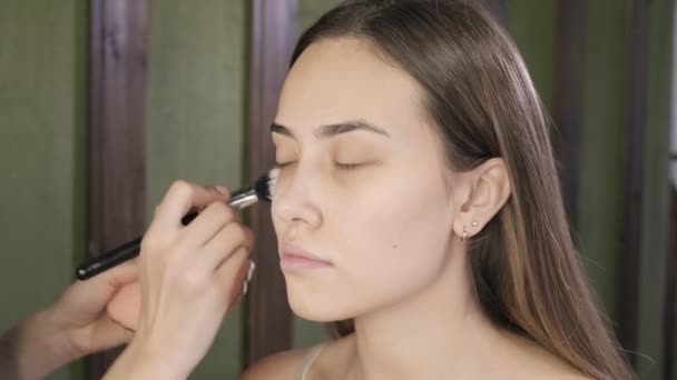 Make up artist doing makeup for brunette asian woman with brush in beauty salon — Stok Video