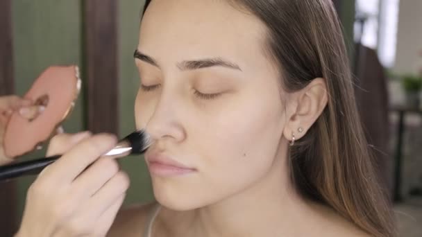 Макіяж художник робить макіяж для брюнетки азіатської жінки з пензлем в салоні краси — стокове відео