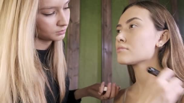 Atraente caucasiano maquiagem artista fazendo maquiagem para asiático feminino no salão de beleza — Vídeo de Stock