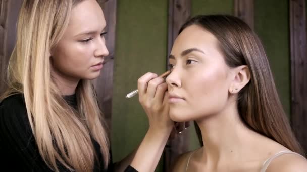 Maquiagem artista fazendo maquiagem para mulher asiática com lápis de olho no salão de beleza — Vídeo de Stock