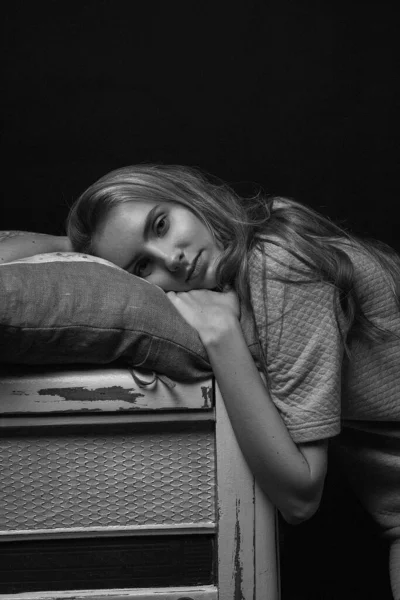 Молода дівчина в сукні лежить на краю коробки на подушці, портрет моделі в приміщенні — стокове фото