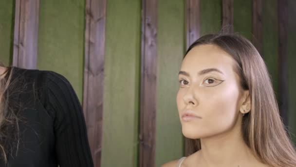 Atractivo caucásico maquillaje artista haciendo maquillaje para asiático femenino en salón de belleza — Vídeo de stock
