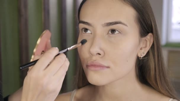 Make-up Artist Make-up für brünette asiatische Frau mit Pinsel im Schönheitssalon — Stockvideo